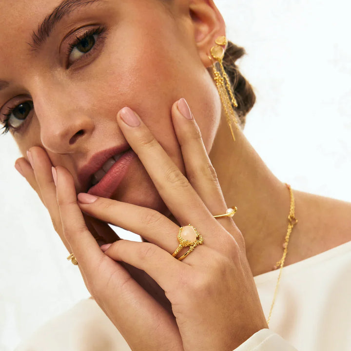 Goldene Ohrringe, Halskette und Ringe mit Perle am Modell, Schmuck in Nahaufnahme