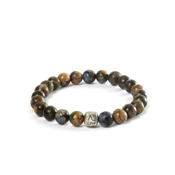 Das Alexander Lynggaard-Armband Glaucophane 8 mm zeigt ein Armband aus runden, braunen und blauen Steinen mit einer Metallperle, Modell c01180-001