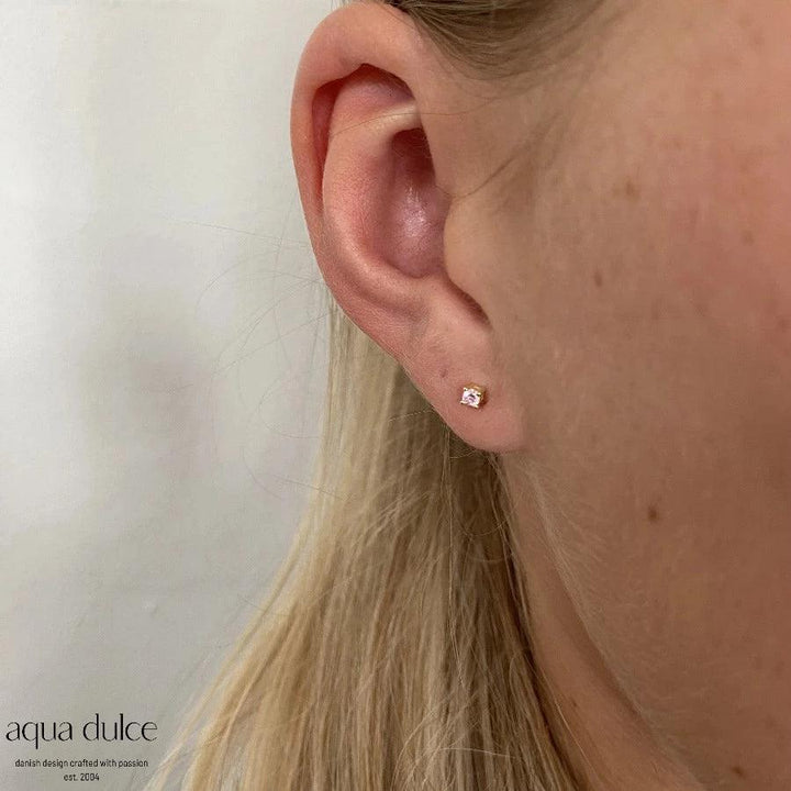 Aqua Dulce Mini Kaya Pink Ohrringe aus vergoldetem Silber sind am Ohr zu sehen, schlichte und feminine Details. Modell 5175-5175-2