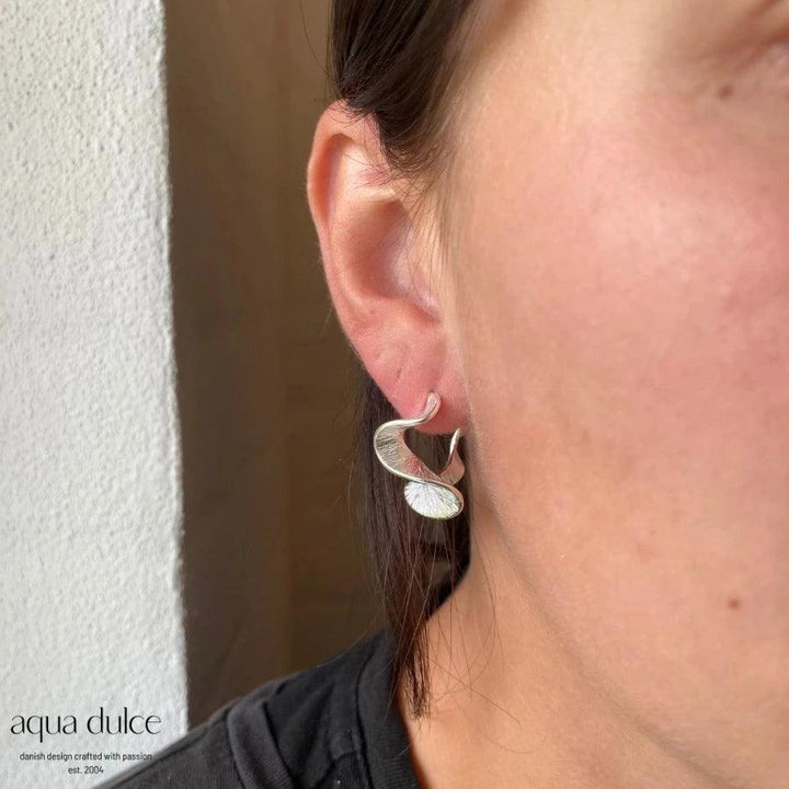 Aqua Dulce Rhumba Medium Hoop in Silber erscheint am Ohr, elegantes Wellendesign. Modell 5319-5319-2
