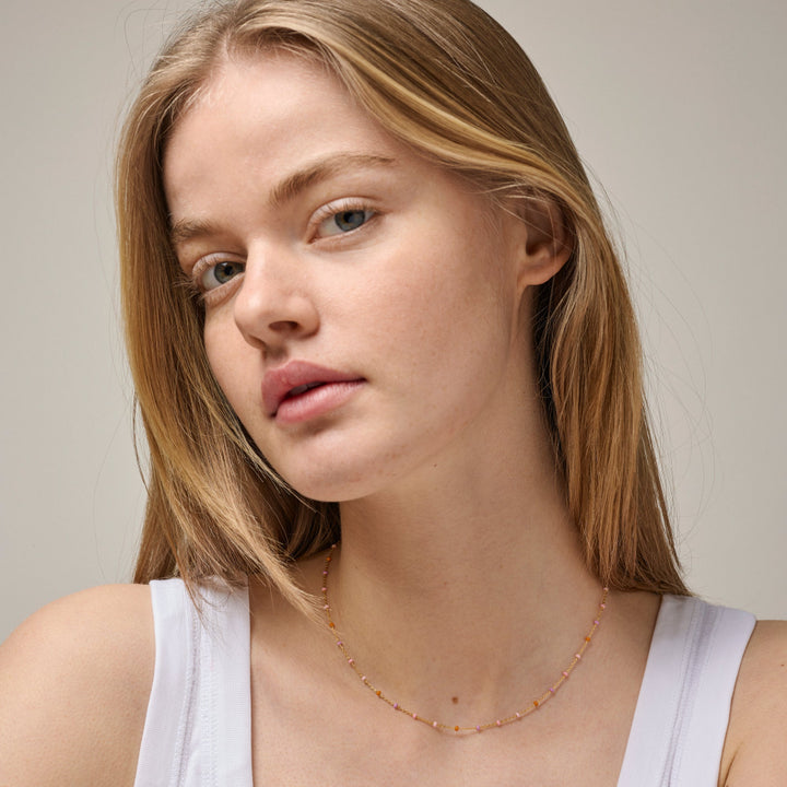 Enamel Lola-Halskette Blush aus vergoldetem Silber, abgebildet am Modell, zarte Rosatöne leuchten leicht. Modell N55G-BLUSH-2