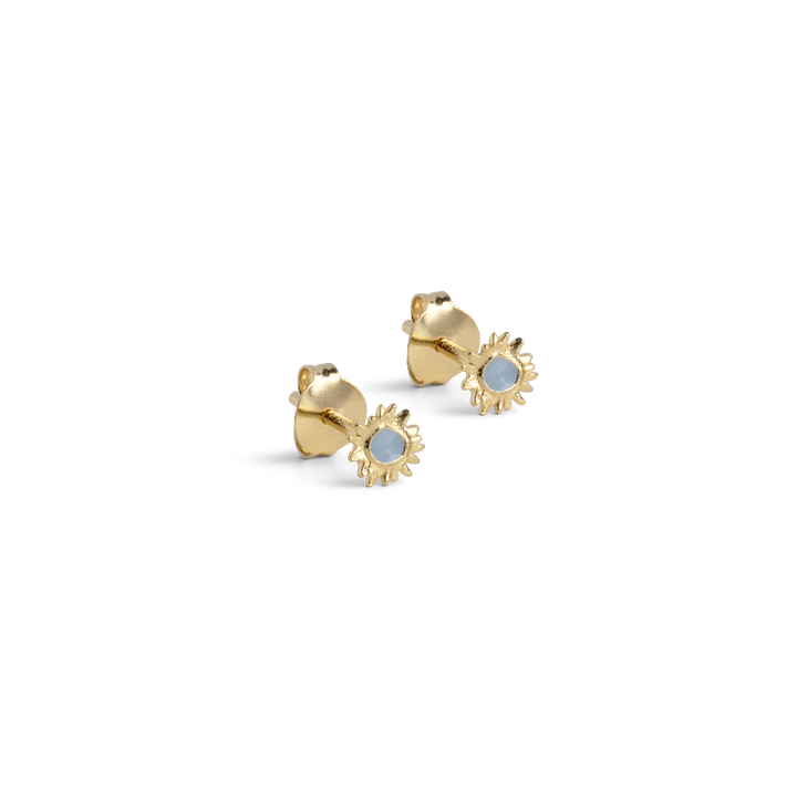 Enamel Mini Sunshine Stud Steel Blue zeigt einen Satz kleiner goldfarbener Ohrstecker mit blauer Emaille. Modell e419g-steelblue-1.