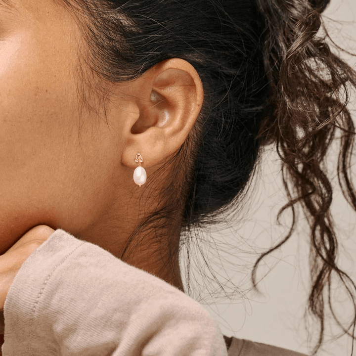 Enamel Hier werden Poe-Perlenohrstecker am Ohr getragen, mit eleganten Süßwasserperlen und goldfarbenen Details. Modell e384gm-pearl