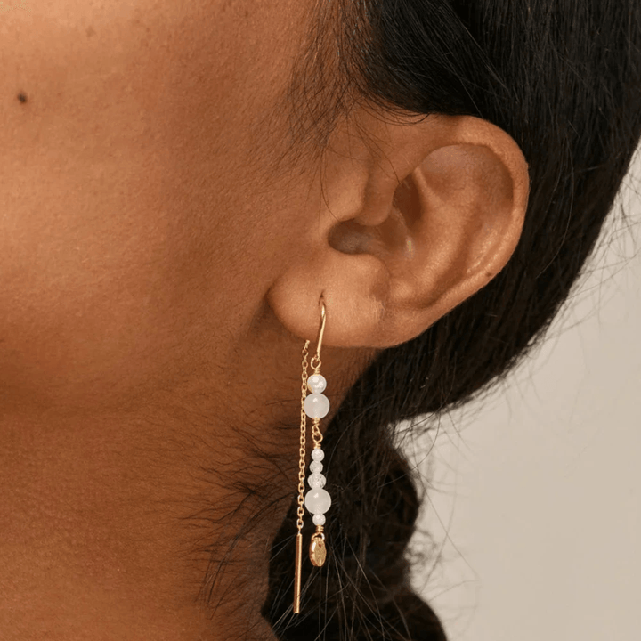Enamel Abgebildet sind die „Sofia Earings White and Pearls“, die im Ohr getragen werden, lange vergoldete Ohrringe mit weißen Perlen. Modell e282g-white-2