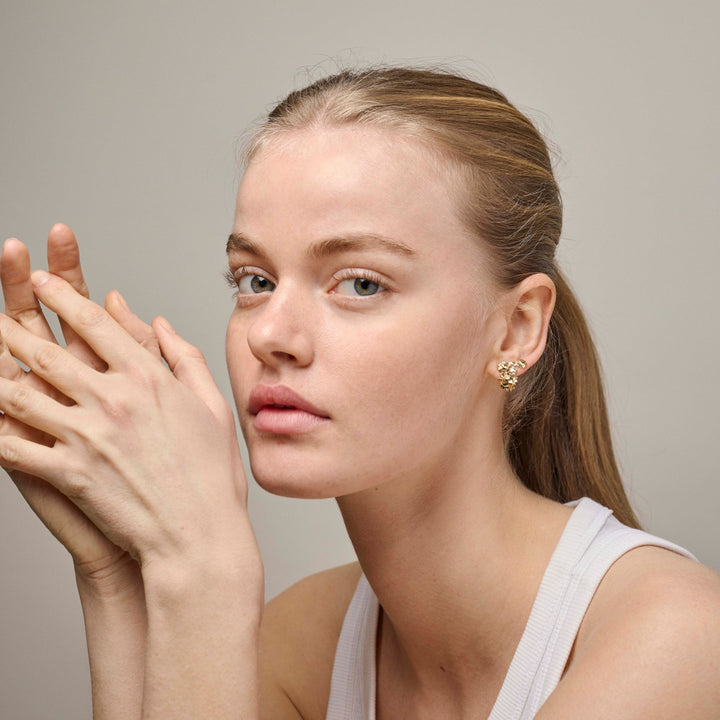 Enamel Sunshine Field Stud e417g wird von einer Frau getragen, goldene Ohrringe in organischer Form. Modell e417g-2