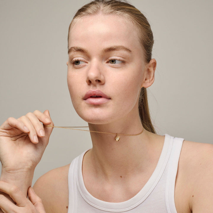 Enamel Sunshine Necklace Daisy n136g erscheint am Hals des Modells, Goldkette mit kleinem Blumenanhänger. Modell n136g-daisy-2