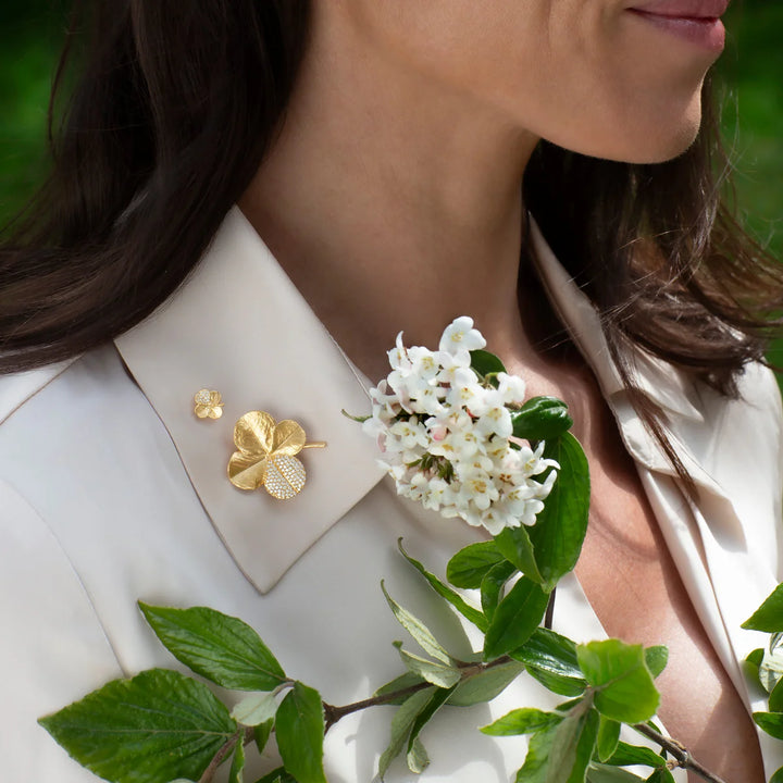 Flora Danica Tannenklee-Pin mit Pavé-Vergoldung wird auf einem hellen Hemd getragen, goldene Details mit Steinen. Modell 907-flc-pi-g-pave-2