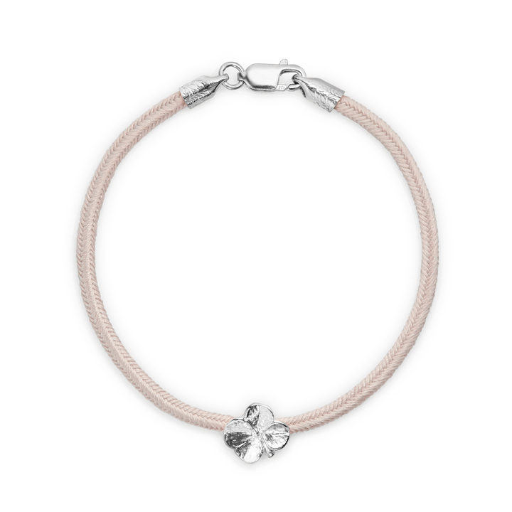 Flora Danica Vierblättriges Kleeblatt-Seidenarmband Pink Silver zeigt ein rosafarbenes Seidenarmband mit einem silbernen vierblättrigen Kleeblatt-Anhänger, Modell 907-flc-silk-rose-s-001.