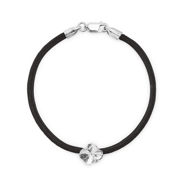 Flora Danica Vierblättriges Kleeblatt-Seidenarmband in Schwarz-Silber mit schwarzer Seidenschnur und silbernem vierblättrigen Kleeblatt-Detail. Modell 907-flc-seide-schwarz-s-001-1