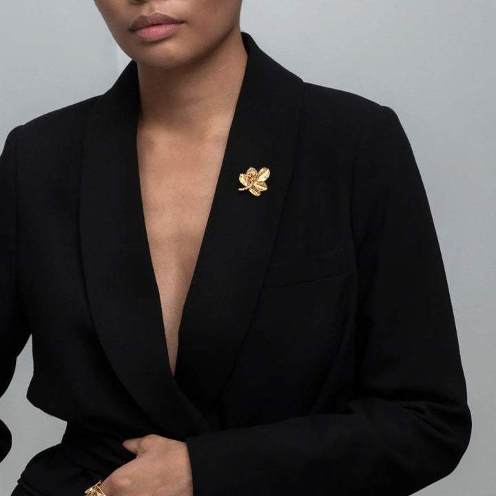 Flora Danica Rosenblad-Brosche. Vergoldete Rosenbrosche auf schwarzem Blazer, elegant und detailliert. Modell bro-g-1