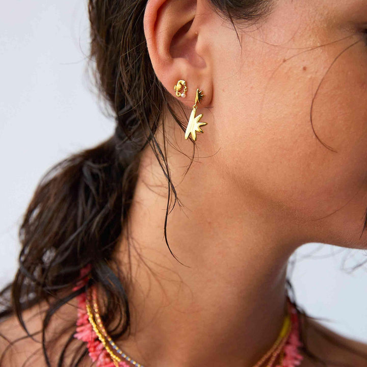 Die vergoldeten Sandy-Ohrringe von Hultquist erscheinen am Ohr der Frau mit sternförmigen Details. Modell S08497G-2