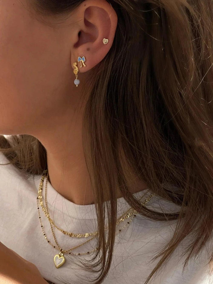 Jeberg Petite Bow Blue Ohrstecker am Ohr abgebildet, blaue Schleife im vergoldeten Design, Modell 52810-2