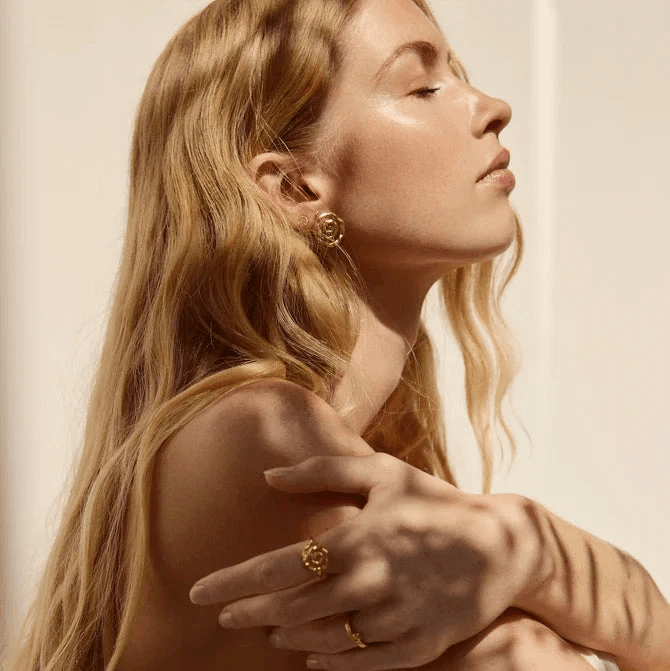 Jeberg Pirouette Darling Ohrringe sind an einer Frau abgebildet, goldene Farbe, eleganter Stil. Modell 52870-2