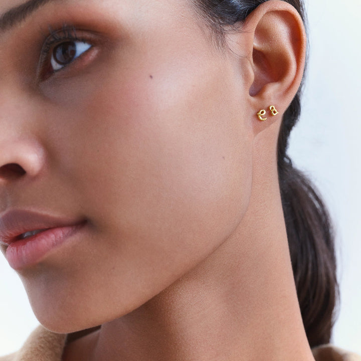 Der Maanesten Alphabet Single Letter Earring AW in vergoldeter Ausführung wirkt im Ohr getragen, eleganter Gold-Look. Modell 101a-alphabet-001-1