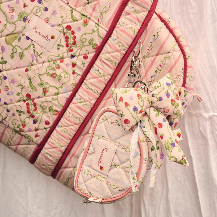 Der Mondstein-Stoffschleifen-Schlüsselanhänger Garden Magic Ivory erscheint auf einer gesteppten Tasche mit Blumen- und Pastelltönen. Modell 4111 – Einheitsgröße