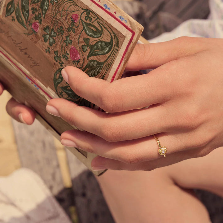 Maanesten Tacita Ring vergoldet, auf der Hand im Sonnenlicht gesehen, schlichter Blumenring in Goldoptik, Modell 4882a-001