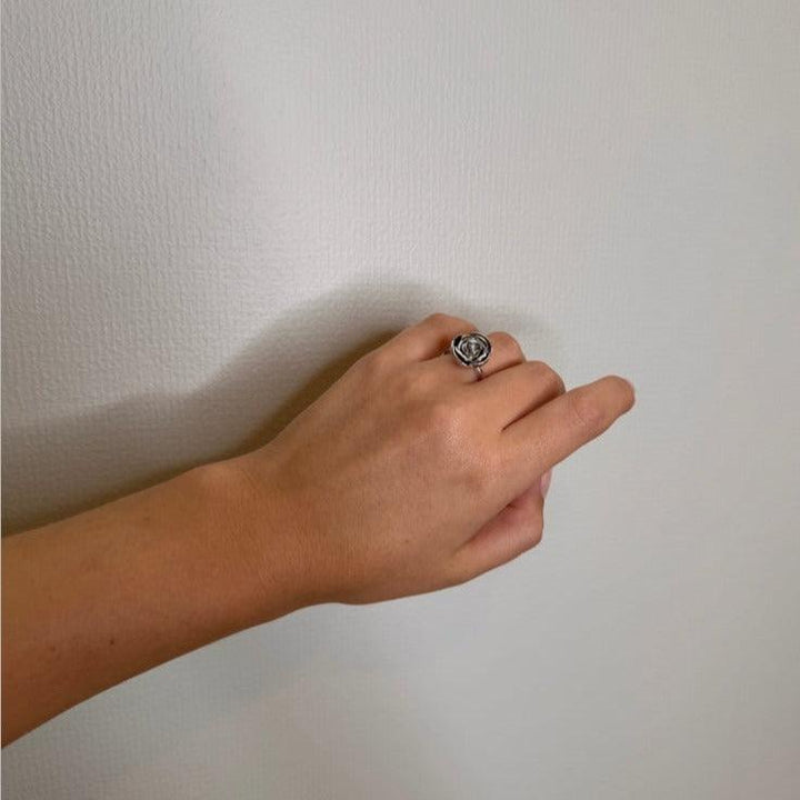 An einer Hand ist der Ring „Rosalie“ von Mads Z Silver mit großer Rose zu sehen, elegant in silberner Ausführung. Modell 2140158-001