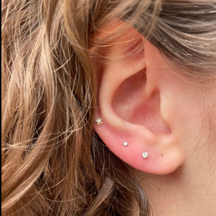 Maria Tash Diamond Solitaire Star Weißgold XSSTARD-WG-W3-001-2 ist im Ohr platziert, sternförmig mit Diamantdetail. Modell XSSTARD-WG-W3-001-2