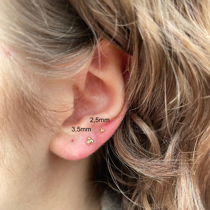 Maria Tash Großer dreikugeliger Trinity-Gewindestecker in Gold, getragen im Ohr, minimalistischer Stil. Modell 35mm-x3btrl-001.