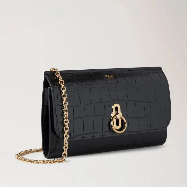 Mulberry Amberley Clutch Black Shiny Small Croc zeigt eine schwarze Clutch aus glänzendem Leder mit Krokodilprägung, goldener Kette und Verschluss. Modell RL8191641A100.
