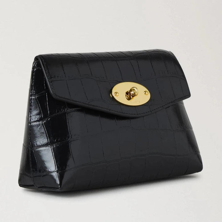 Mulberry Darley Cosmetic Pouch Black Shiny Small Croc zeigt eine schwarze Kosmetiktasche aus glänzendem Krokodilleder mit einer goldenen Schnalle. Modell RL8187641A100