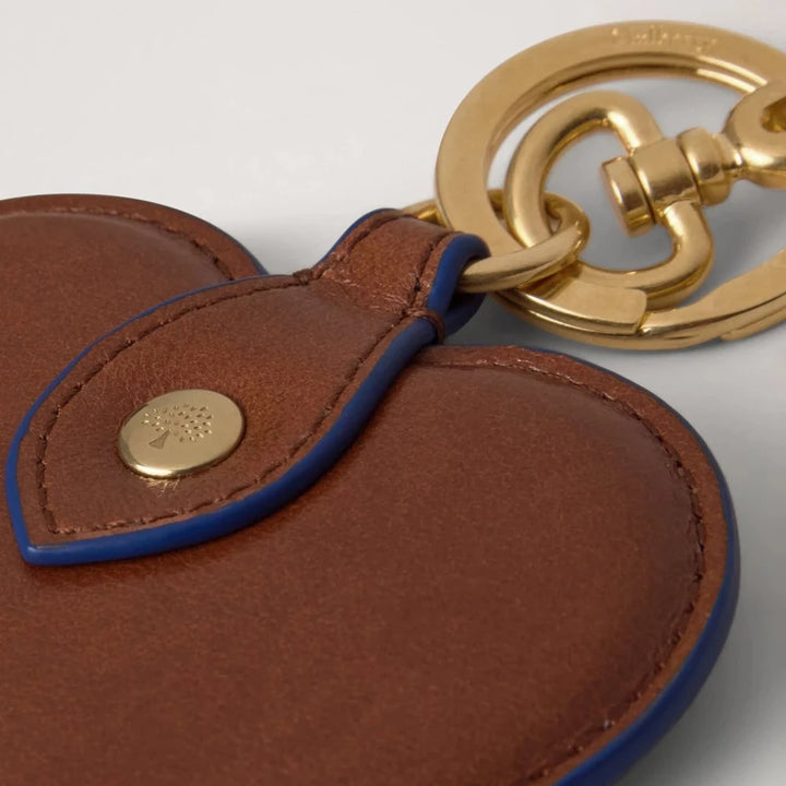 Mulberry Der Heart Keyring Oak/Pigment Blue zeigt einen Schlüsselanhänger aus braunem Leder mit blauem Besatz und goldfarbenem Verschluss, Modell rk6003562g231.