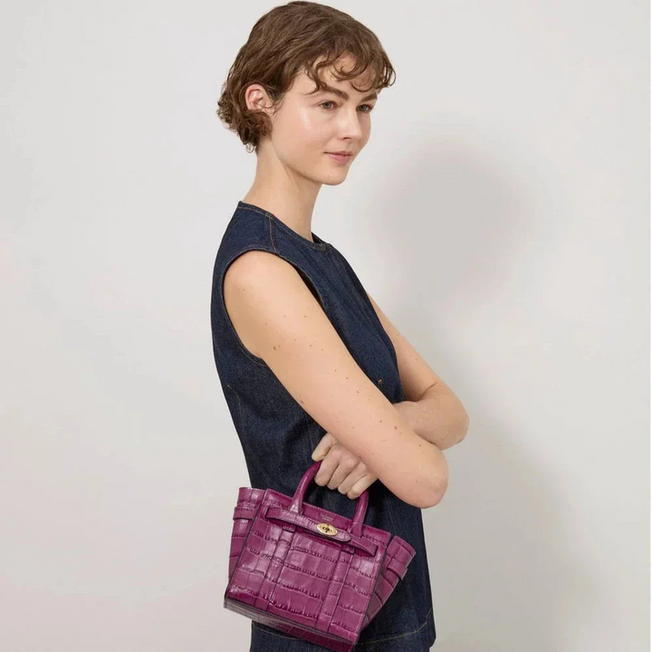 Mulberry Mikro-Reißverschluss Bayswater Das Orchid Bloom Shiny Small Croc wird in der Hand einer Frau getragen. Modell RL8691641J512