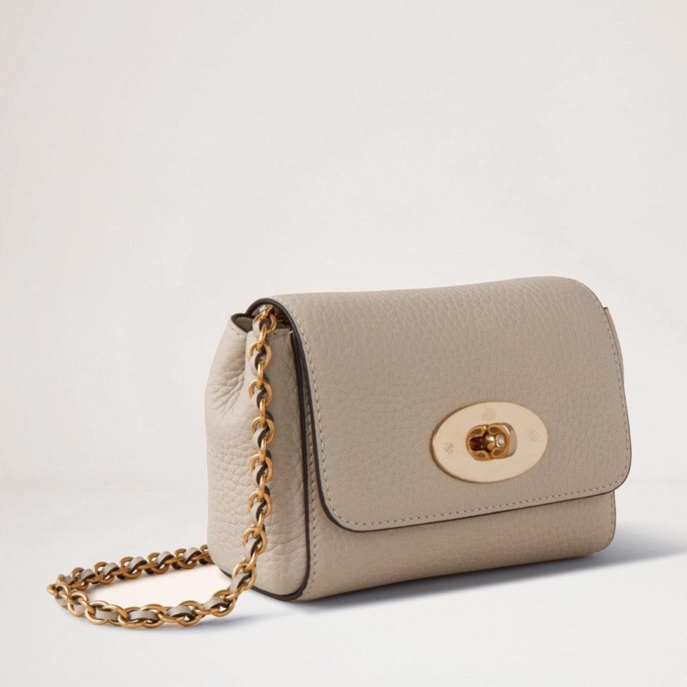 Mulberry Mini Lily Heavy Grain Chalk zeigt eine kleine, beige Umhängetasche aus schwerem Leder mit Kettenriemen und goldener Schnalle. Modell RL7944736W160.