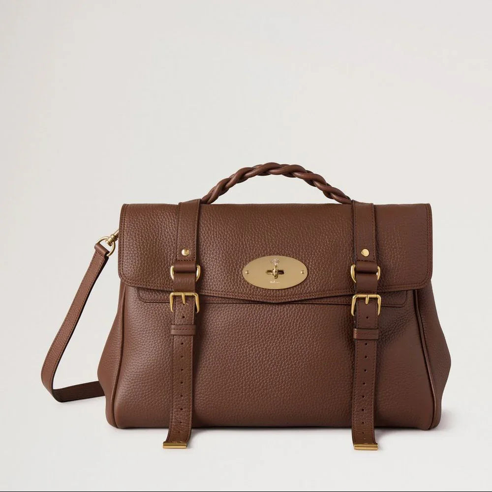 Mulberry Die übergroße Alexa Bright Oak Heavy Grain zeigt eine große braune Ledertasche mit geflochtenem Griff und goldfarbener Schnalle. Modell HH6884/736G222