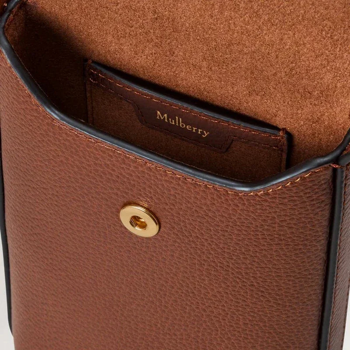 Mulberry Telefontasche mit Druckknopf aus Eichenholz mit Nahaufnahme der braunen Lederoberfläche und goldfarbenem Druckknopf, Modell RL9007552G110