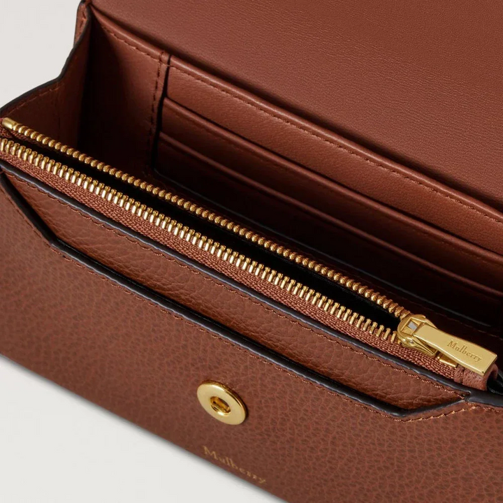 Mulberry Press Stud Wallet Oak Small Classic Grain zeigt eine Nahaufnahme einer braunen Lederbrieftasche mit goldenen Details und Kartenfach, Modell RL9008552G110.
