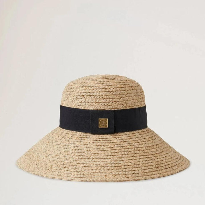 Mulberry Raffia Sun Hat Wide Brim zeigt einen naturfarbenen Strohhut mit einem breiten schwarzen Band. Modell VH4136060H120-001-1