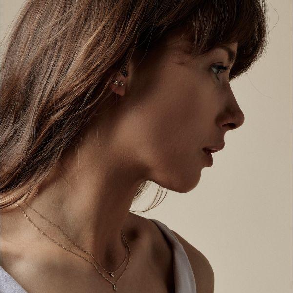 Nuran 14kt Zoe Ohrringe erscheinen dezent am Ohr einer Frau, schlicht und elegant in Gold. Modell o2314-006rg-2.