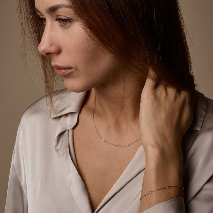 Nuran Zoe 14-karätiges Armband mit Diamanten, getragen von einer Frau in einem hellbraunen Hemd am Handgelenk. Modell b1002-0125-2