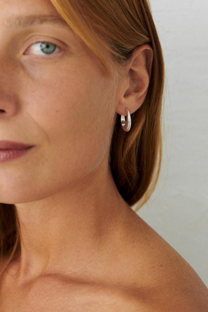 Pernille Corydon Globe Huggies in Silber, getragen vom Model, schlichter und eleganter Stil. Modell E-401-S