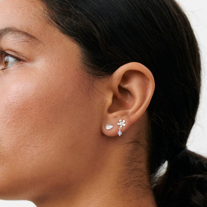 Pernille Corydon Meadow Earring Box in Silber ist im Ohr des Modells abgebildet, glänzende Oberfläche und Blumendetail. Modell C-121-S-1.