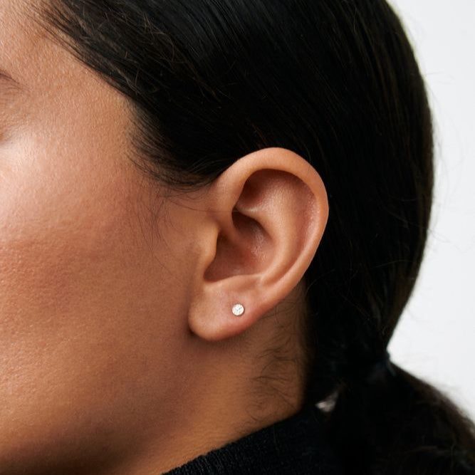 Pernille Corydon Micro Nature Ohrstecker aus vergoldetem Silber, am Ohr in Nahaufnahme abgebildet. Modell E-390-GP