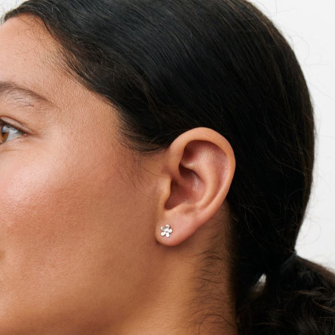 Pernille Corydon Mini Wild Poppy Ohrstecker zeigen einen silbernen, blütenförmigen Ohrring am Modell. Modell E-369-S