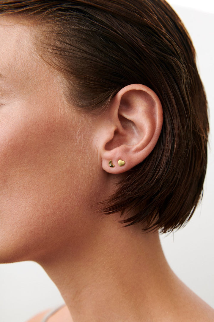 Am Ohr sind Pernille Corydon Night Light Earsticks abgebildet, kleine vergoldete Earsticks in minimalistischem Design. Modell C-122-GP-2