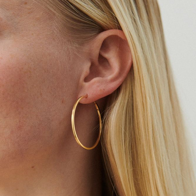 Pernille Corydon Small Orbit Hoops vergoldet, am Ohr getragen, schlanker runder goldener Ohrring. Modell E-052-GP.