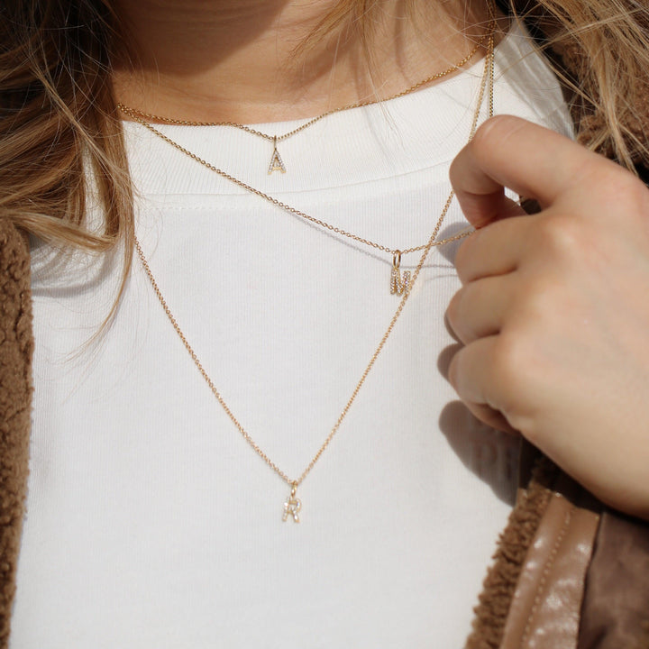 ro copenhagen Meine Kollektion mit Diamanten, Goldketten mit Buchstabenanhänger, getragen auf einer weißen Bluse, Modell p114y2-001-2