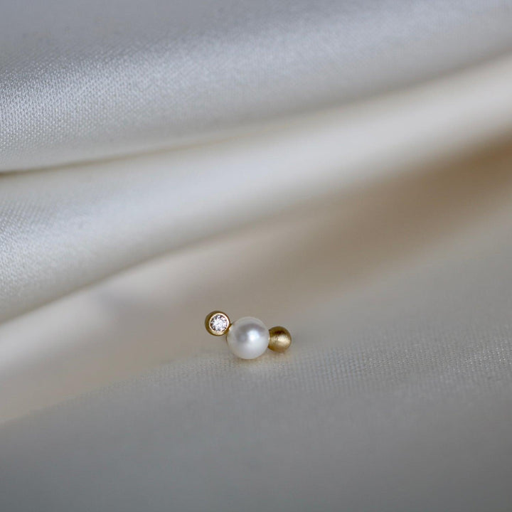 RO Copenhagen Die Orbit Dot WWF Ohrstecker verfügen über ein einzelnes Perlen-, Diamant- und Golddetail auf hellem Stoff. Modell E118Y103-2