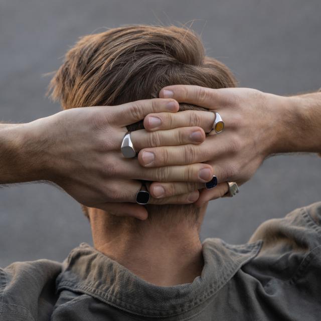 Herrenring „Son of Noa“ aus poliertem Silber an der Hand eines Mannes im natürlichen Außenlicht. Modell 125104-9-001-2