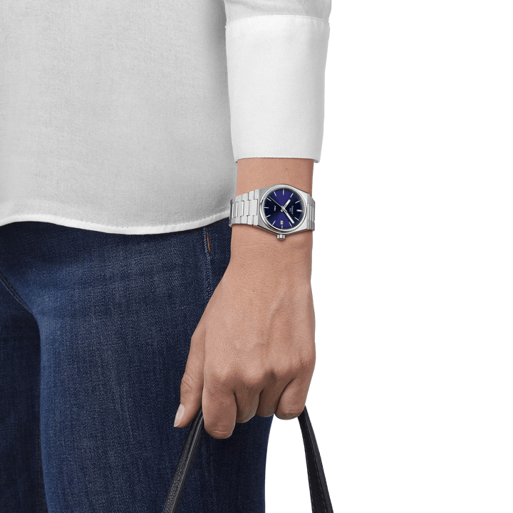 Tissot PRX mit blauem Zifferblatt am Handgelenk, Stahlkette und lässigem Stil, Modell T1372101104100.