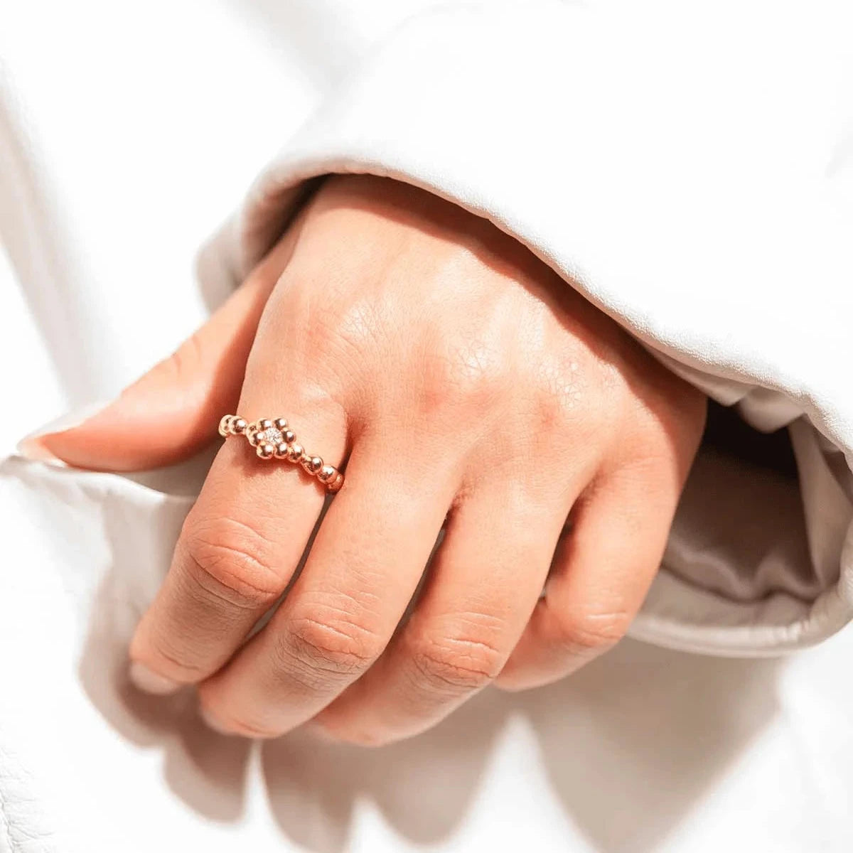 Vincent Bloom Ring vergoldet mit weißem Kristall, an der Hand getragen, goldfarbener Perlenring mit klaren Steinen, Modell VJ253-URG-001-1.