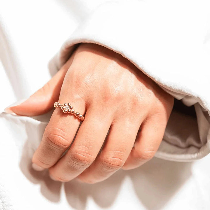 Vincent Bloom Ring vergoldet mit weißem Kristall, an der Hand getragen, goldfarbener Perlenring mit klaren Steinen, Modell VJ253-URG-001-1.