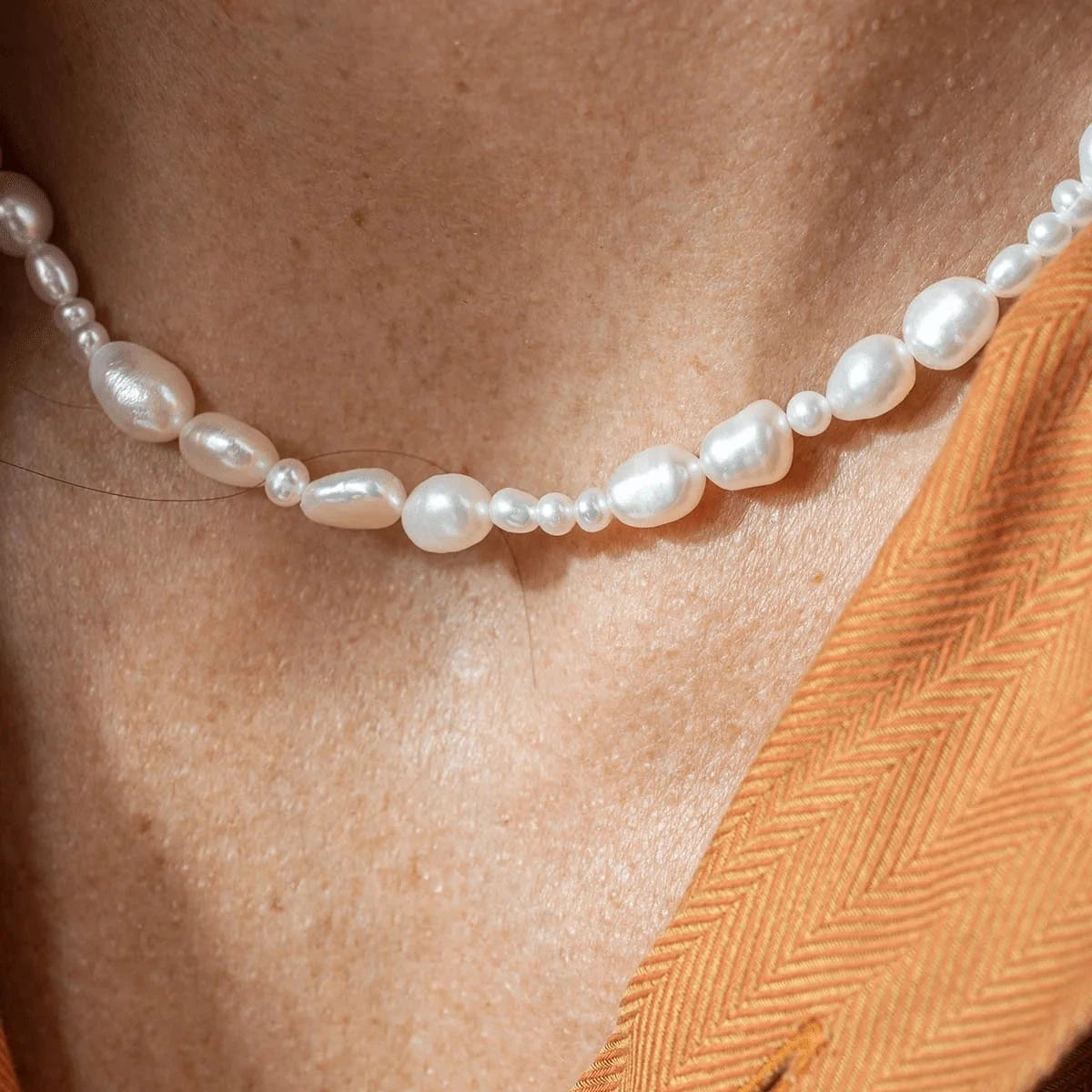 Vincent Venus Conspiracy vergoldete Perlenkette. Nahe am Hals dargestellt, unregelmäßige weiße Perlen. Modell VJ087