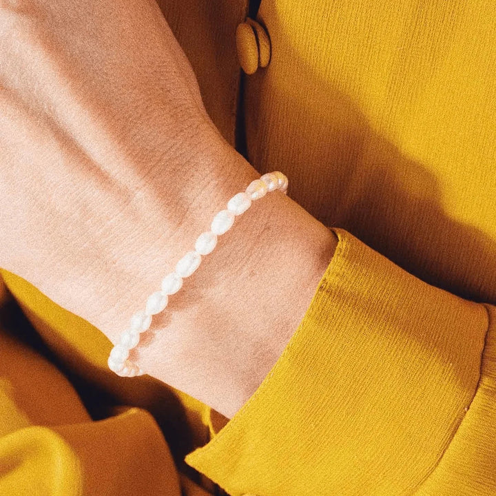 Das vergoldete Perlenarmband von Vincent Venus wird um das Handgelenk getragen, die weißen Perlen sind deutlich sichtbar. Modell VJ082-UBG-1