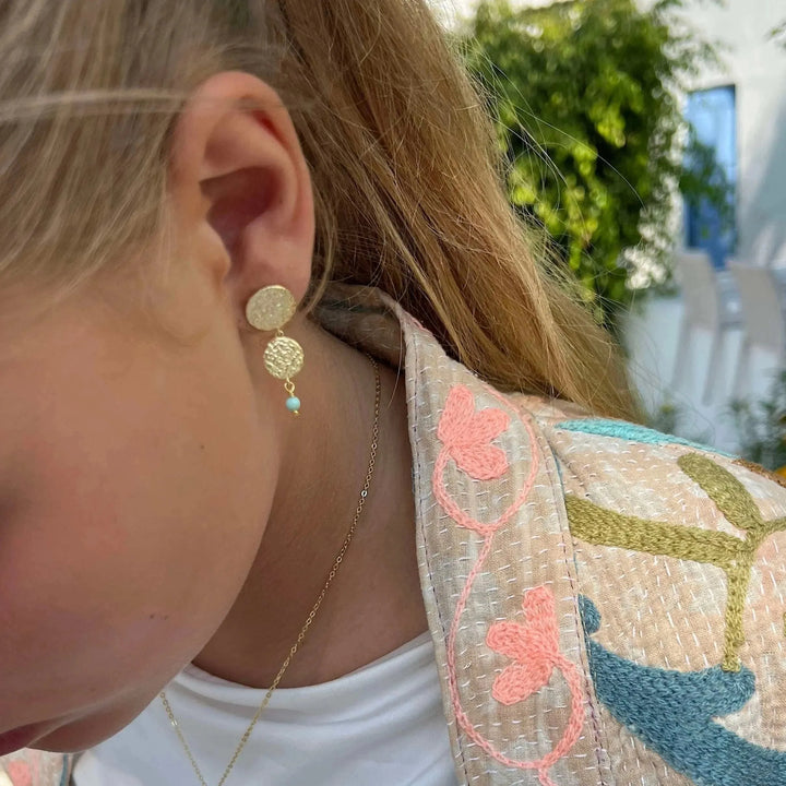 Sisse Marie-Ohrstecker mit goldenen Plättchen und blauer Lapisperle werden im Freien getragen, Modell E-8804-GP.