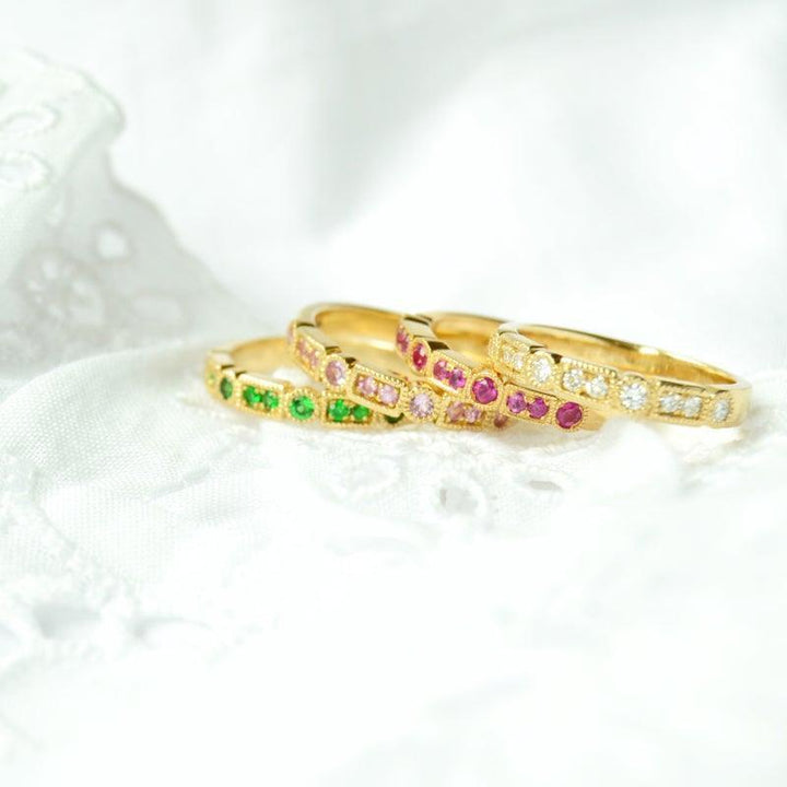 anpe-atelier-trine-ji-green-ring-14kt-gold-der Ring liegt vorne, elegant mit grünen Steinen, in 14 kt Gold auf weißem Stoff. Modell 2500-001-2